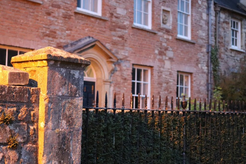 A historic stone house with a wrought iron fence.