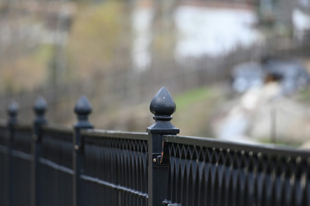 a close up of a fence with a building in the background